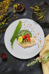 Halibut fillet with spinach, asparagus, and cherry tomatoes, shot with moody lighting and overhead composition