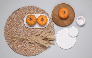 Autumn moodboard with pumpkin, dried lagurus flowers and plaster figures on a straw woven rug. Flat...