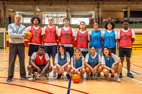 High school basketball team posing with coach in gymnasium
