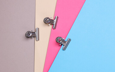 Metal binders paper clips on colored paper background
