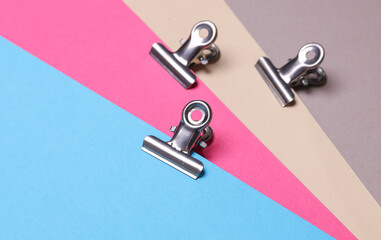 Metal binders paper clips on colored paper background