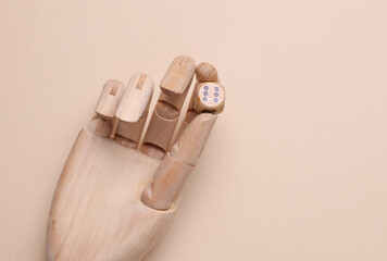 Puppet's hand holding wooden dice on beige background