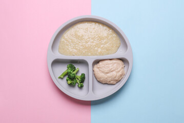 Baby food divider plate with healthy food on pink blue background