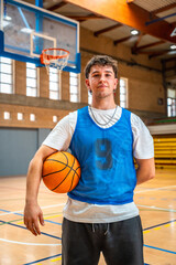 Naklejka premium Basketball player holding ball in indoor court posing after training