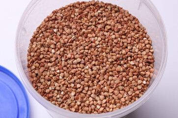 Plastic jar with buckwheat on white background. Top view