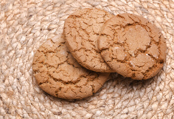 Three oatmeal cookies on a straw mat