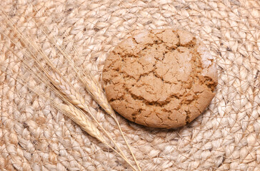 Oatmeal cookie with wheat ears on a straw mat