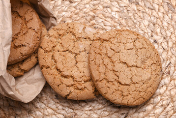 Oatmeal cookies in paper bag on a straw mat