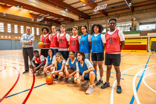 High school basketball team posing with coach on court