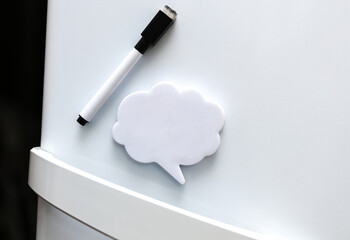 White magnet in the form of a dialog cloud for notes and reminders on the refrigerator door