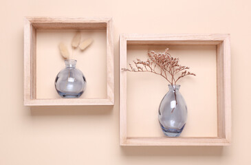 Two glass vases with dried flowers in wooden square shelves on beige background. Minimalistic aesthetic still life.