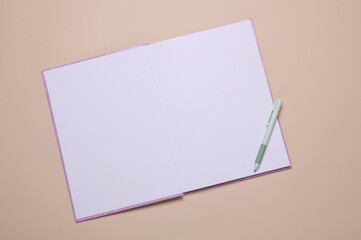 Open notebook or diary with white blank pages for mockup, pen on beige background. Top view