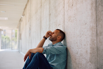 Exhausted entrepreneur sitting on floor after stressful day at work.