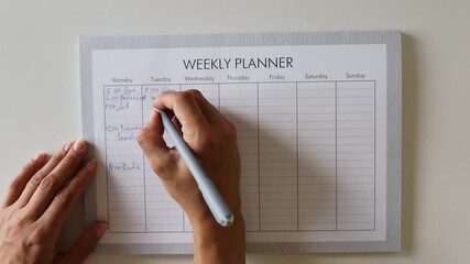 A woman's hand writes down events on a weekly planner. Making a plan for the week