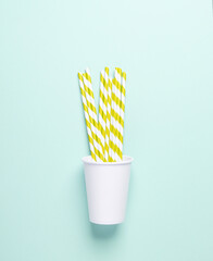 White cardboard cup with straws on a blue background. Party, birthday accessories