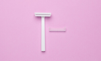 Disposable white plastic razor on pink background. Top view