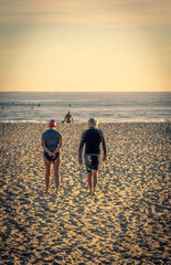 An older couple walking down to the water for an early morning swim.