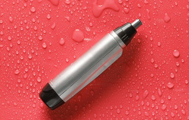 Nose razor on red background with water drops.