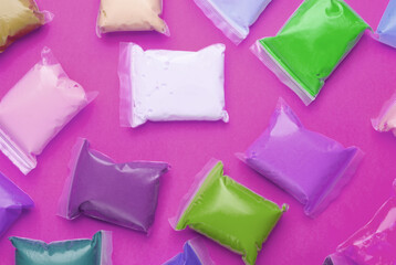Colored Air plasticine set in packs, purple background. Children's creativity. Top view.