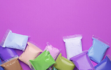 Air plasticine set in packs, purple background. Children's creativity. Top view. Copy space