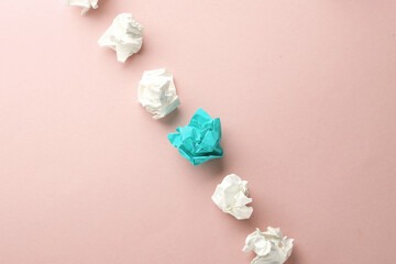Crumpled white and blue balls of paper on a pink background. Leadership, uniqueness, business...