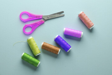 Scissors with skeins of thread on a blue background. Sewing accessories. Top view
