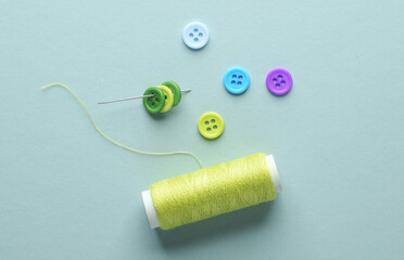 Skein of yellow thread and a needle, buttons on lavender blue background. Sewing accessories