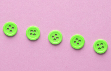Plastic green buttons on a pink background