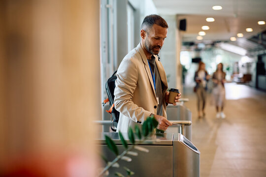 Smiling businessman using access card while entering office building.