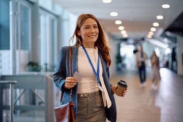 Happy businesswoman carrying takeaway coffee while coming to work in office.