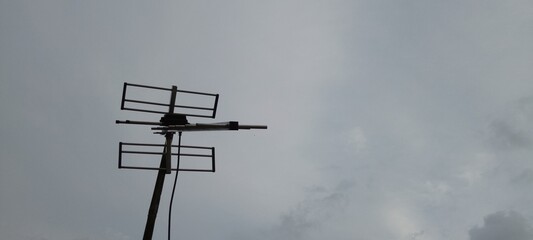 Old Television Antenna on Bamboo Pole with White Sky Background, Vintage TV Aerial Setup in Rural Area, Traditional Signal Receiver and Retro Technology Concept