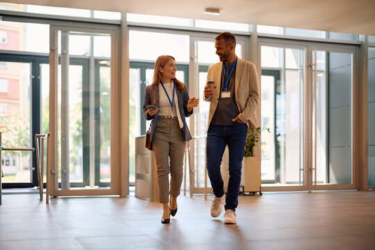 Happy businesswoman and her colleague talking while entering office building.