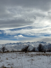 Snow covered mountains in Kyrgyzstan under cloudy winter sky peaceful rural landscape