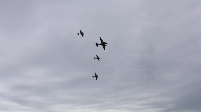 Flying formation cloudy sky vintage aircraft military parade warbirds teamwork precision aviation airshow performance nostalgic dramatic iconic scene flight history