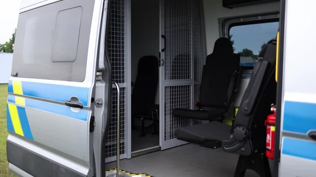 Police transport van interior with steel cage seating area and secured layout open door revealing secure setup for detainee transfer law enforcement vehicle prepared for duty