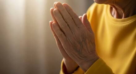 Close Up Of Elderly Person Hands Folded In Prayer With Bright Sunlight Streaming Over The Yellow Shirt