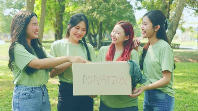 Group female volunteers together carry cardboard boxes in a park collect donations help victims natural disasters, wars and poor and homeless. They are happy volunteer with their cheerful appearance.
