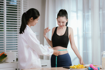 A professional, possibly a nutritionist or trainer, measures a happy woman's waist, indicating a health and wellness check.