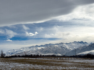 Snow covered mountains in Kyrgyzstan under cloudy winter sky peaceful rural landscape