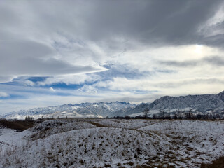 Snow covered mountains in Kyrgyzstan under cloudy winter sky peaceful rural landscape