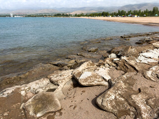 Rocky shore and clear water of Issyk-Kul under a vast sky