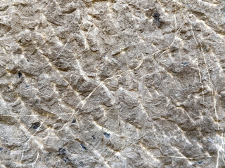 Rough textured beige stone surface with natural cracks and patterns