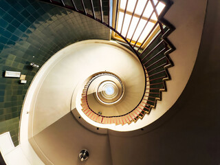 Spiral staircase with green tiled wall and natural light from window
