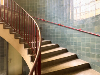 Curved staircase with red railing in tiled interior