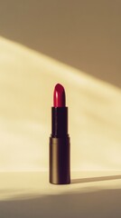 A close-up of a vibrant red lipstick in a black tube, placed against a soft, neutral background with gentle lighting.