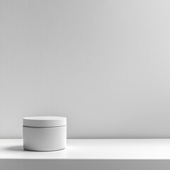 A simple white round container sits on a clean, minimalistic shelf against a plain gray wall. The design is modern and elegant, emphasizing simplicity.
