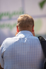A man with a bald head is wearing a blue shirt with a plaid pattern