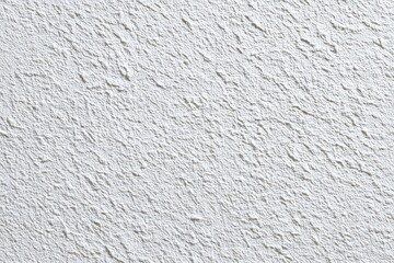 A close-up shot of a textured, off-white wall with a rough, uneven surface, showing a variety of small bumps and crevices