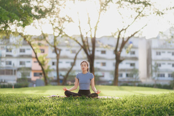 A young woman in workout attire practices yoga in a peaceful pose at a public park. The soft...