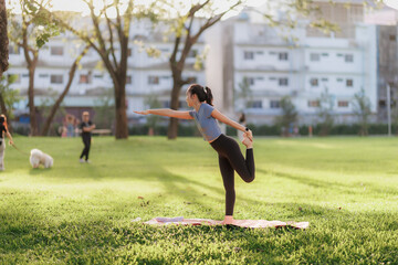 A young woman in workout attire practices yoga in a peaceful pose at a public park. The soft...